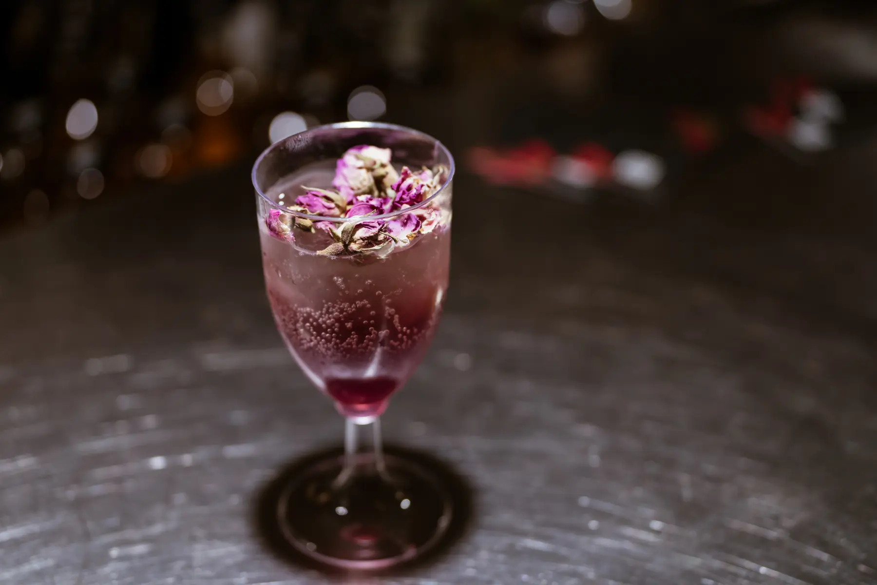 A rose-toned signature spritz garnished with dried rosebuds